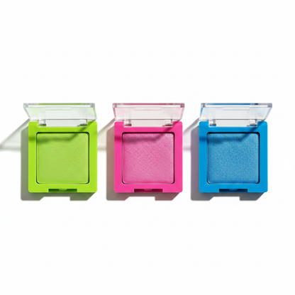 Three color-matched eyeshadow compacts in neon lime green, hot pink fuchsia and electric cobalt blue open flat lay