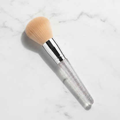 Top-down flat lay view of crystal glitter handle powder brush on marble surface