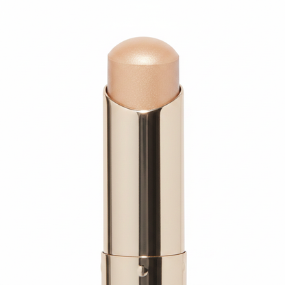 Close-up of rounded dome nude beige cream tip and twist joint detail on polished champagne gold metal concealer stick