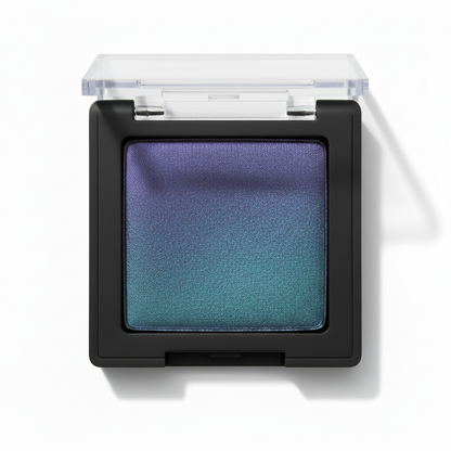 Square black compact with clear lid open showing violet purple to teal green duochrome gradient shimmer eyeshadow
