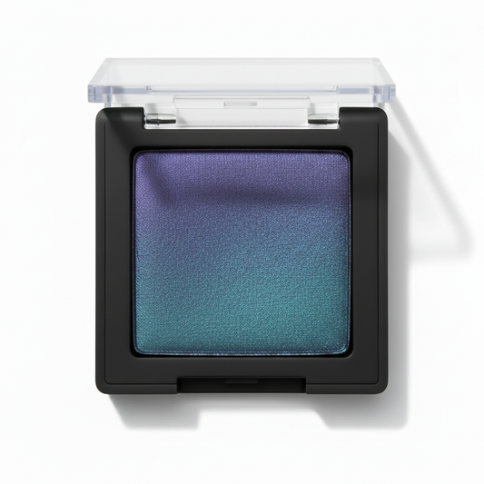 Square black compact with clear lid open showing violet purple to teal green duochrome gradient shimmer eyeshadow